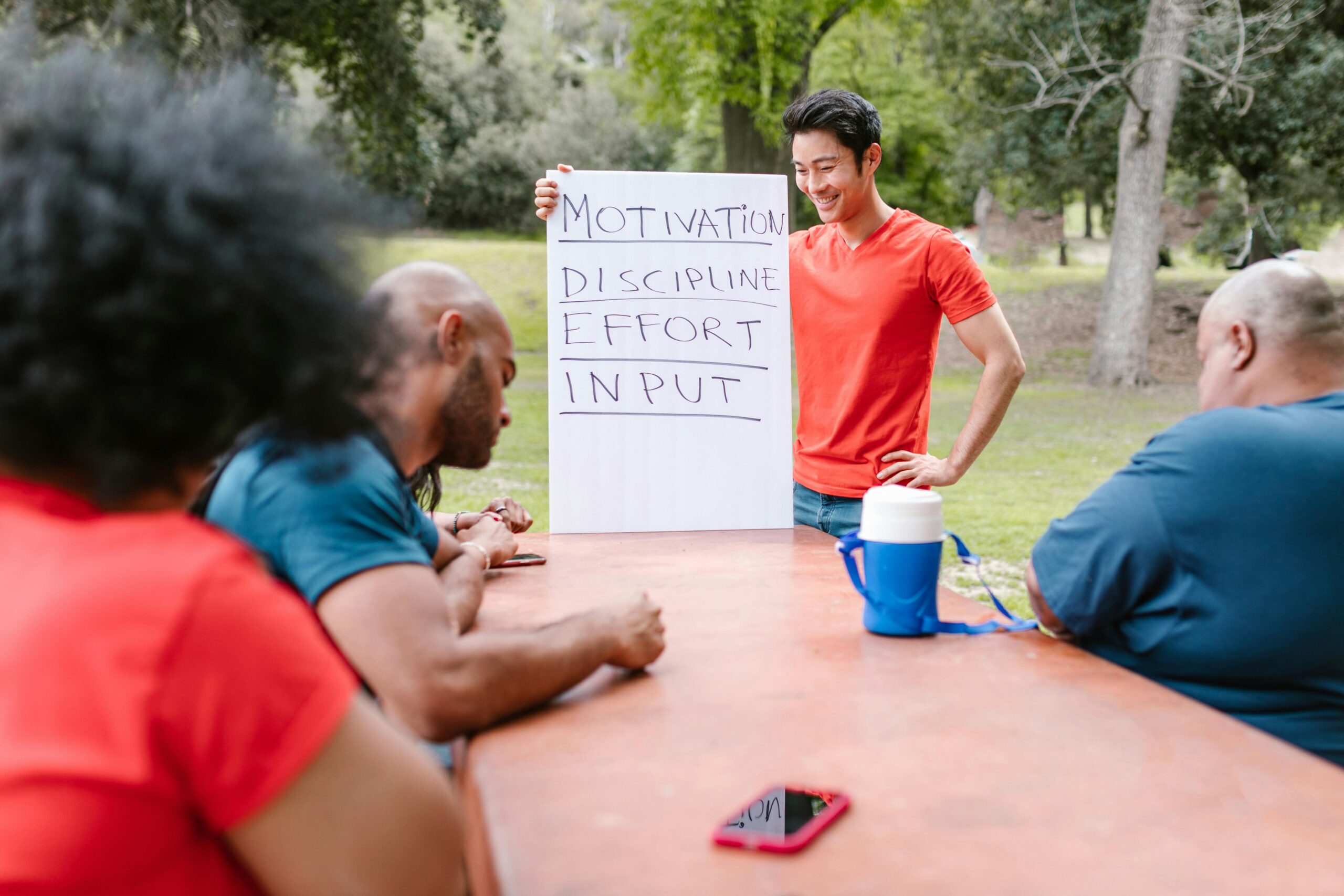 Home A diverse group of adults engaged in a motivational team building session outdoors.